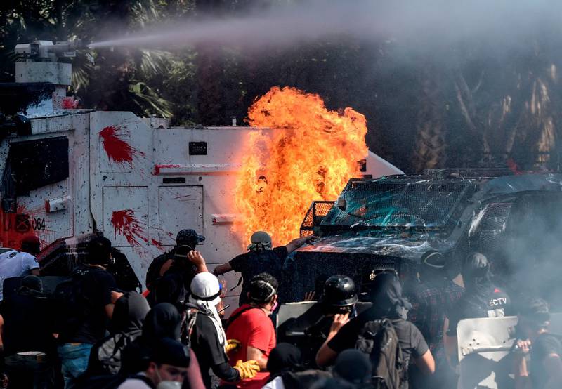 Demonstrators set a riot police vehicle on fire during clashes on the commemoration of the first anniversary of the social uprising in Chile, in Santiago.  AFP
