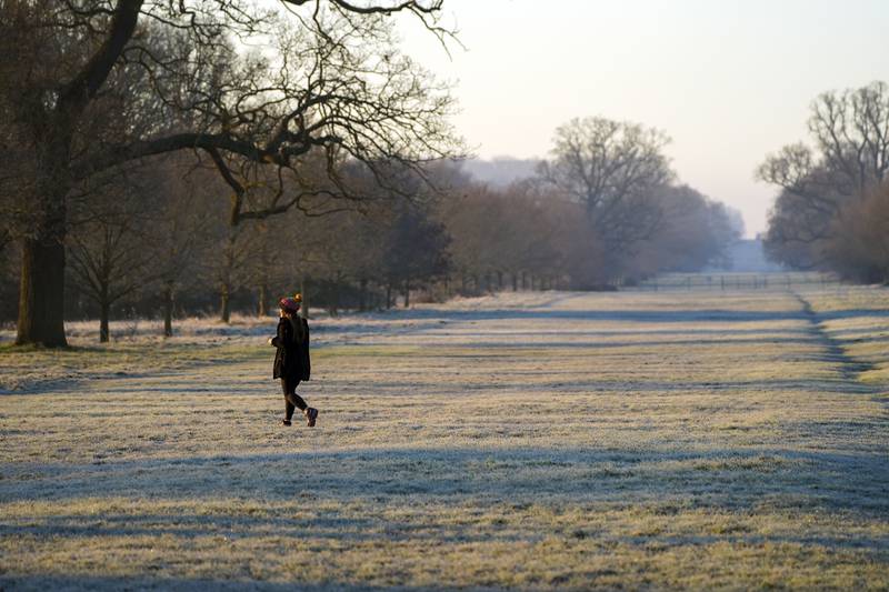 A person walks over frosted grass in Windsor Great Park, Berkshire. The Met Office said the West Midlands, East Midlands, East, South East and South West are also set to experience colder temperatures through Sunday. PA