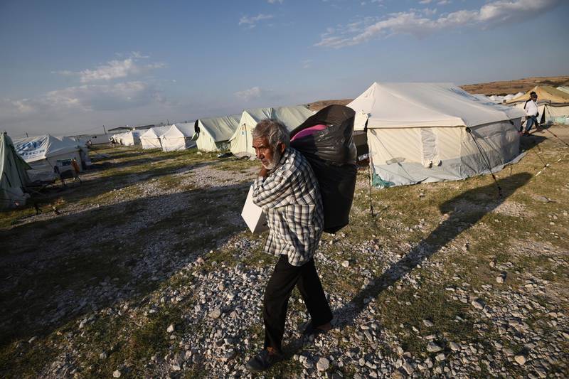 A migrant carries his belongings at a refugee camp in Nea Kavala, northern Greece. About 1,500 asylum-seekers transported from Greece's eastern Aegean island of Lesbos to the mainland. Around 1,000 of those transferred and housed in Nea Kavala, where they will be staying in tents until the end of the month, after which they will be transferred to a new camp under construction. AP