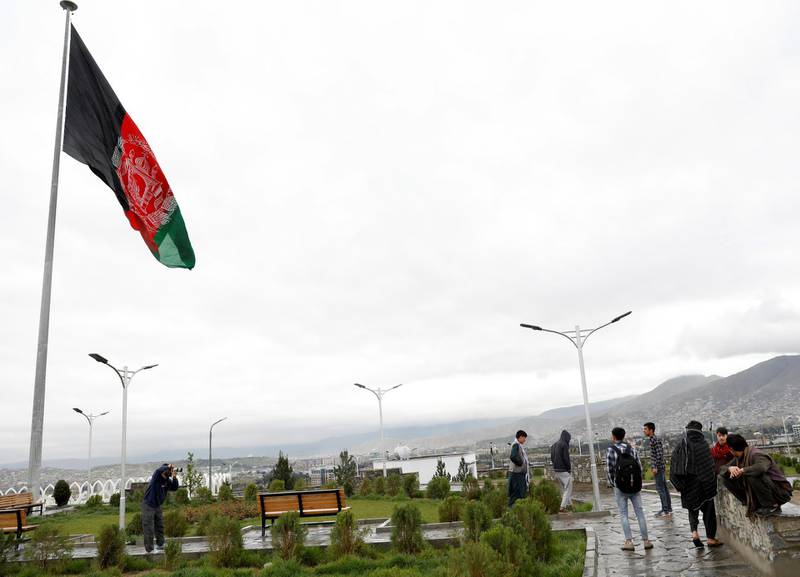 Youths take pictures near an Afghan flag on a hilltop overlooking Kabul, Afghanistan, April 15. Reuters