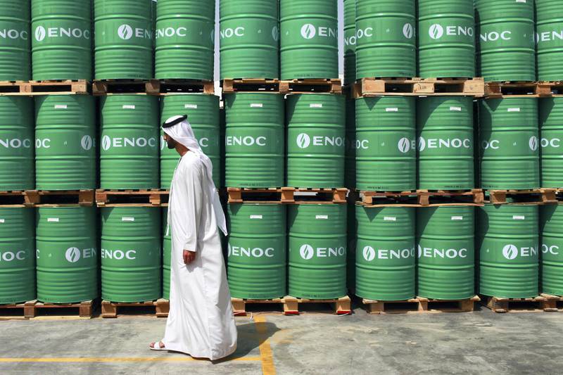 A visitor passes ENOC-branded oil barrels stored at the Emirates National Oil Co. lubricants and grease manufacturing plant in Fujairah, United Arab Emirates, on Monday, March 12, 2012. ENOC, as Dubai's government-owned refiner is known, will expand the plant's capacity to 250,000 tons a year by 2014, it said. Photographer: Gabriela Maj/Bloomberg
