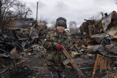 Yehor, 7, holds a toy rifle next to destroyed Russian military vehicles near Chernihiv on Sunday, April 17. AP
