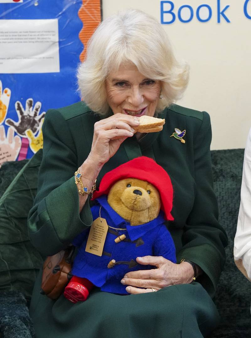 The queen consort eats a marmalade sandwich, with Paddington on her lap. Marmalade sandwiches are the fictional bear's favourite food. PA