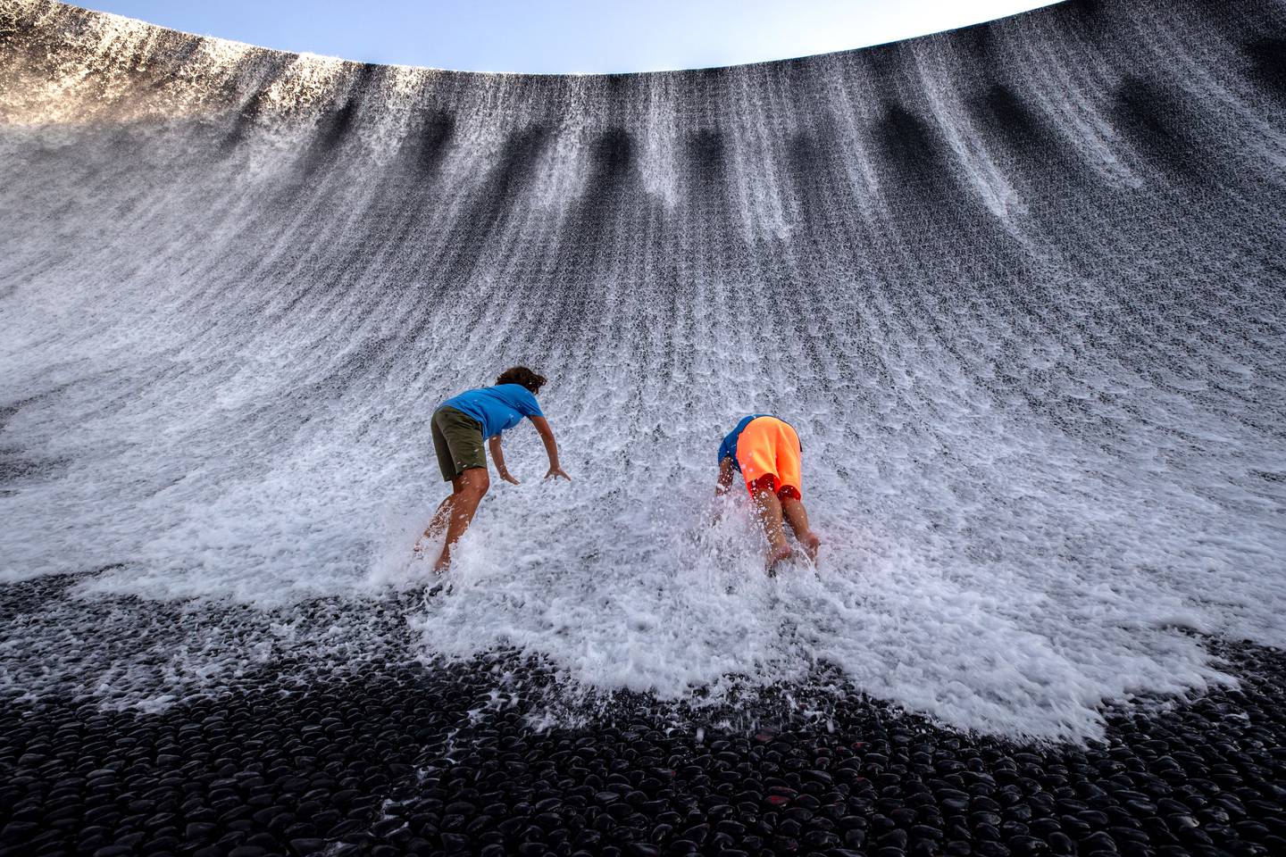 Children attempt to scale the stone walls of the water installation on the Expo site. Victor Besa / The National.
