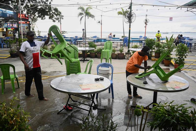 Workers clean chairs and tables at a food centre as businesses reopened in Penang, Malaysia. AFP