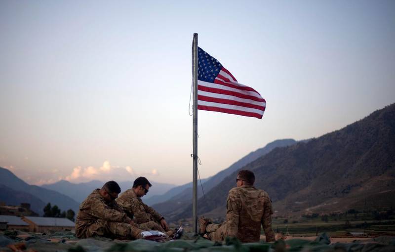 FILE - In this Sept. 11, 2011 file photo, US soldiers sit beneath an American flag just raised to commemorate the tenth anniversary of the 9/11 attacks at Forward Operating Base Bostick in Kunar province, Afghanistan. The Biden administrationâ€™s surprise announcement in April 2021, of an unconditional troop withdrawal from Afghanistan by Sept. 11, 2021, appears to strip the Taliban and the Afghan government of considerable leverage, pressuring them to reach a peace deal. (AP Photo/David Goldman, File)