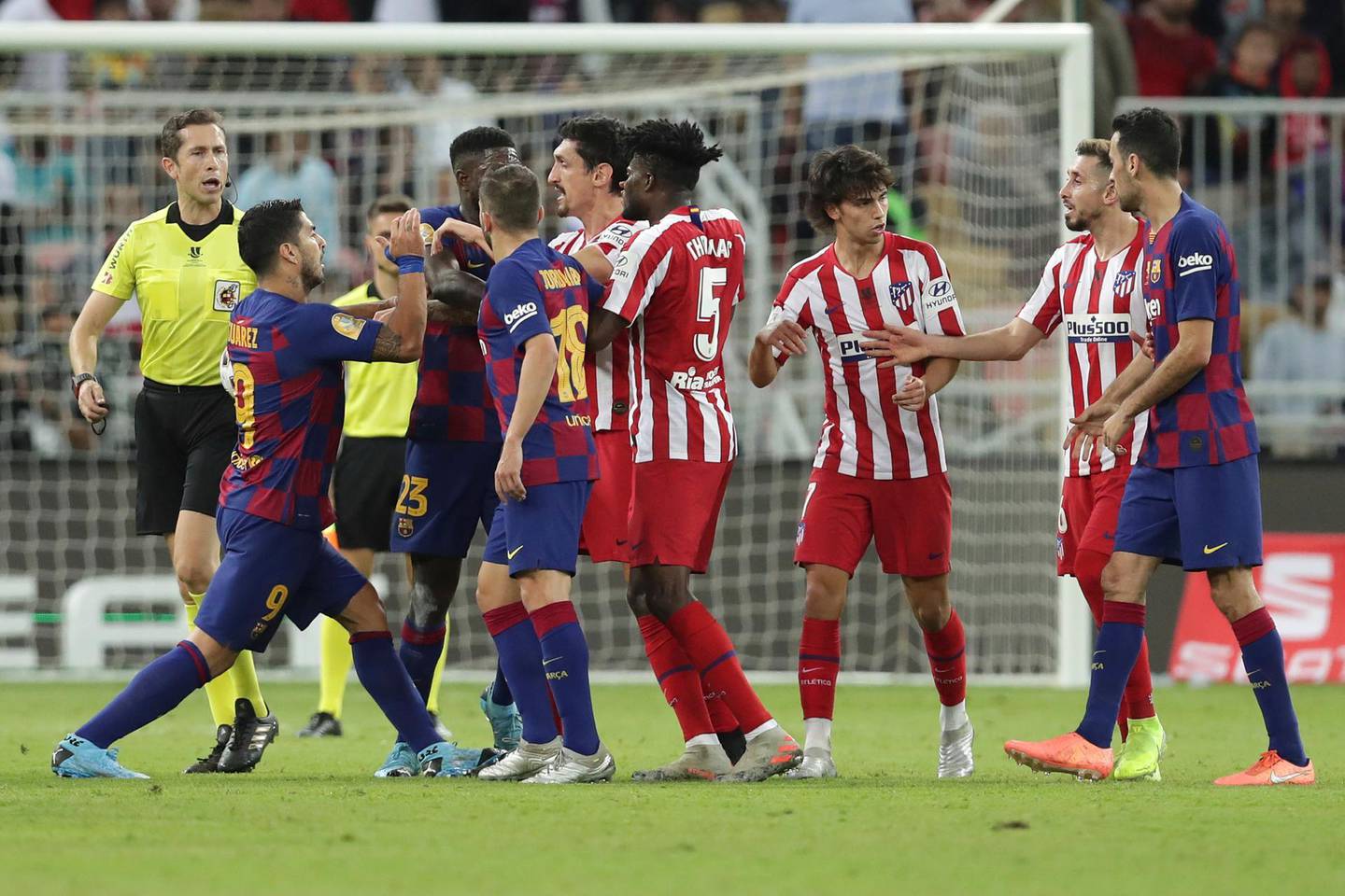 Barcelona's Luis Suarez, left, fights with Atletico Madrid's Stefan Savic, center, during the Spanish Super Cup semifinal soccer match between Barcelona and Atletico Madrid at King Abdullah stadium in Jiddah, Saudi Arabia, Thursday, Jan. 9, 2020. (AP Photo/Hassan Ammar)