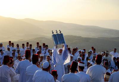 A Samaritan priest raises the Torah scroll as worshippers gather to pray at sunrise during a Passover ceremony on top of Mount Gerizim, near the northern West Bank town of Nablus. AFP