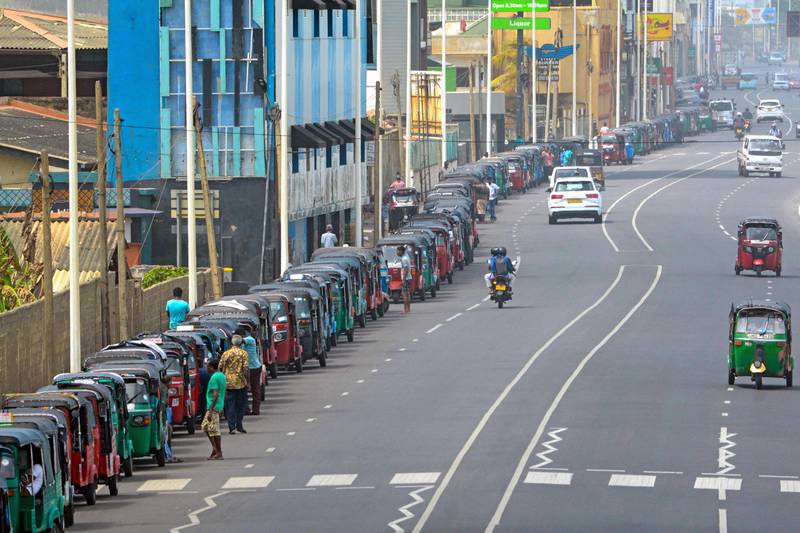 Motorised rickshaw drivers queue along a street to buy petrol from a fuel station in Colombo. AFP