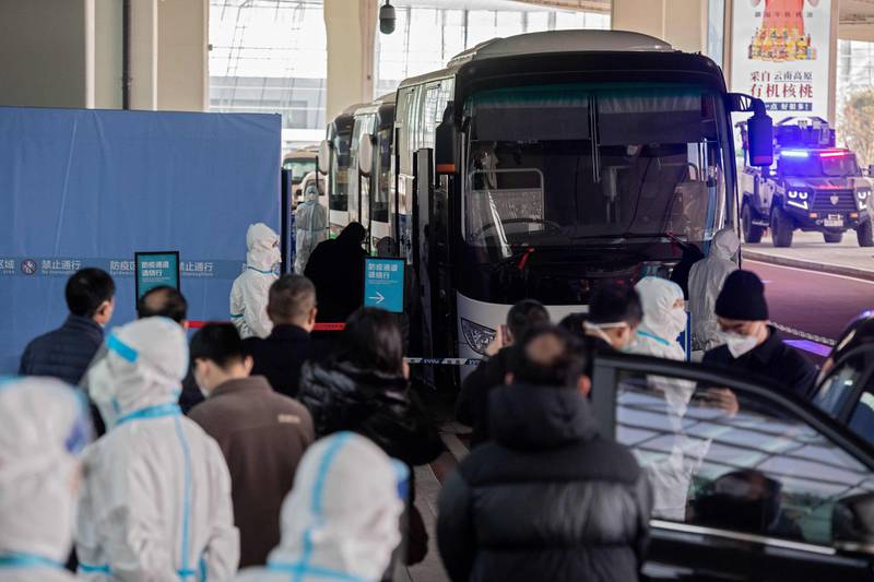 Members of the World Health Organisation team investigating the origins of the Covid-19 pandemic board a bus following their arrival at a cordoned-off section in the international arrivals area at the airport in Wuhan. AFP