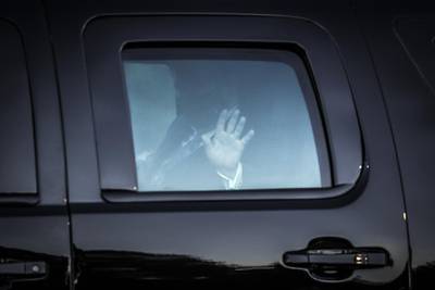 US President Donald Trump waves from the presidential motorcade while arriving at the Walter Reed National Military Medical Center. Bloomberg