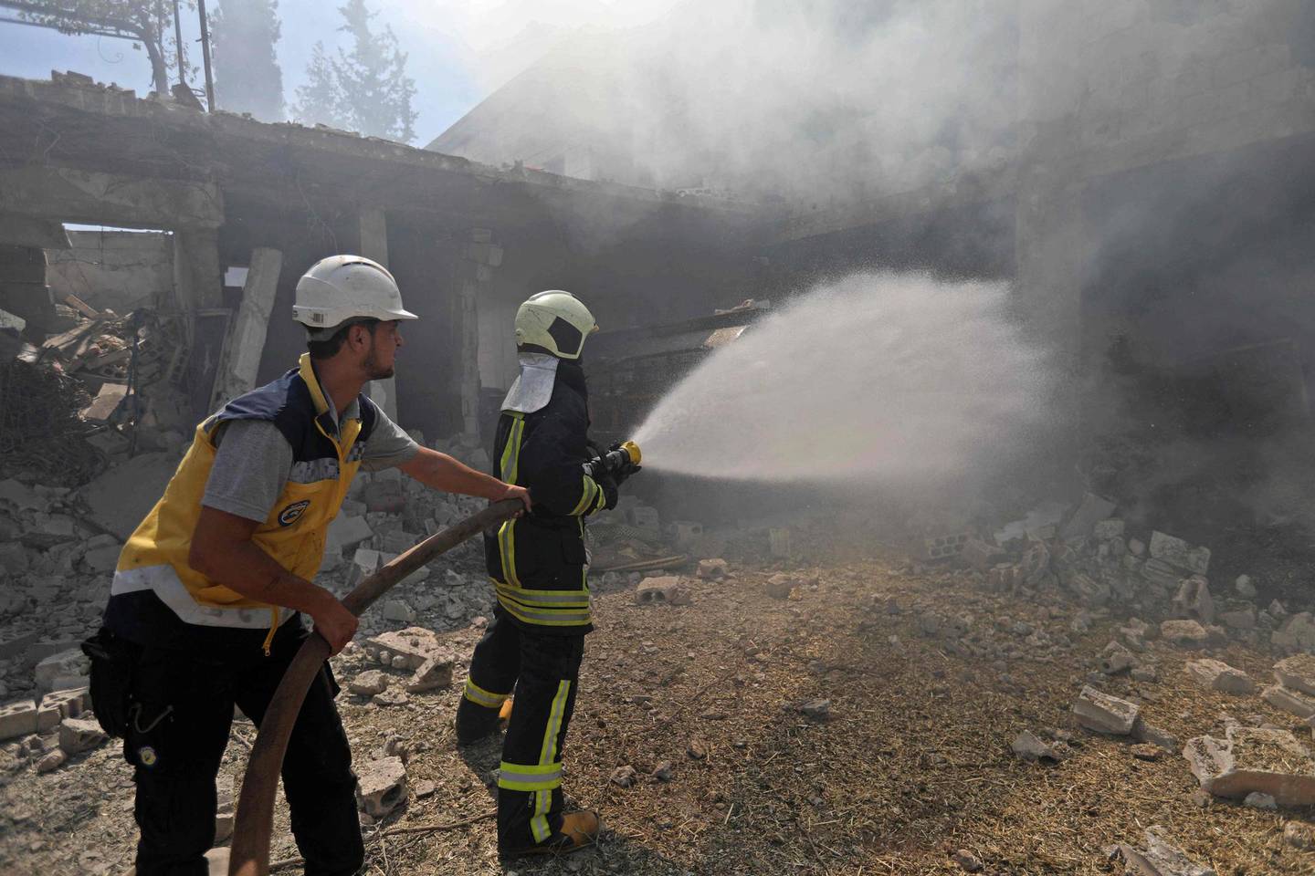 Syrian firefighters try put out a fire in a building that was hit by reported Russian air strikes in the rebel-hold town of Jadraya, about 35 kilometres southwest of the city of Idlib, on September 4, 2018. - Russian warplanes battered Syria's rebel-controlled northwestern Idlib province on September 4 for the first time in three weeks, the Syrian Observatory for Human Rights reported, as fears of a government offensive mount. (Photo by OMAR HAJ KADOUR / AFP)