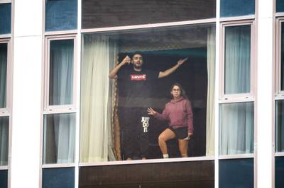 A couple gesture to the media from their room at the Radisson Blu Edwardian hotel, near Heathrow Airport. Getty Images