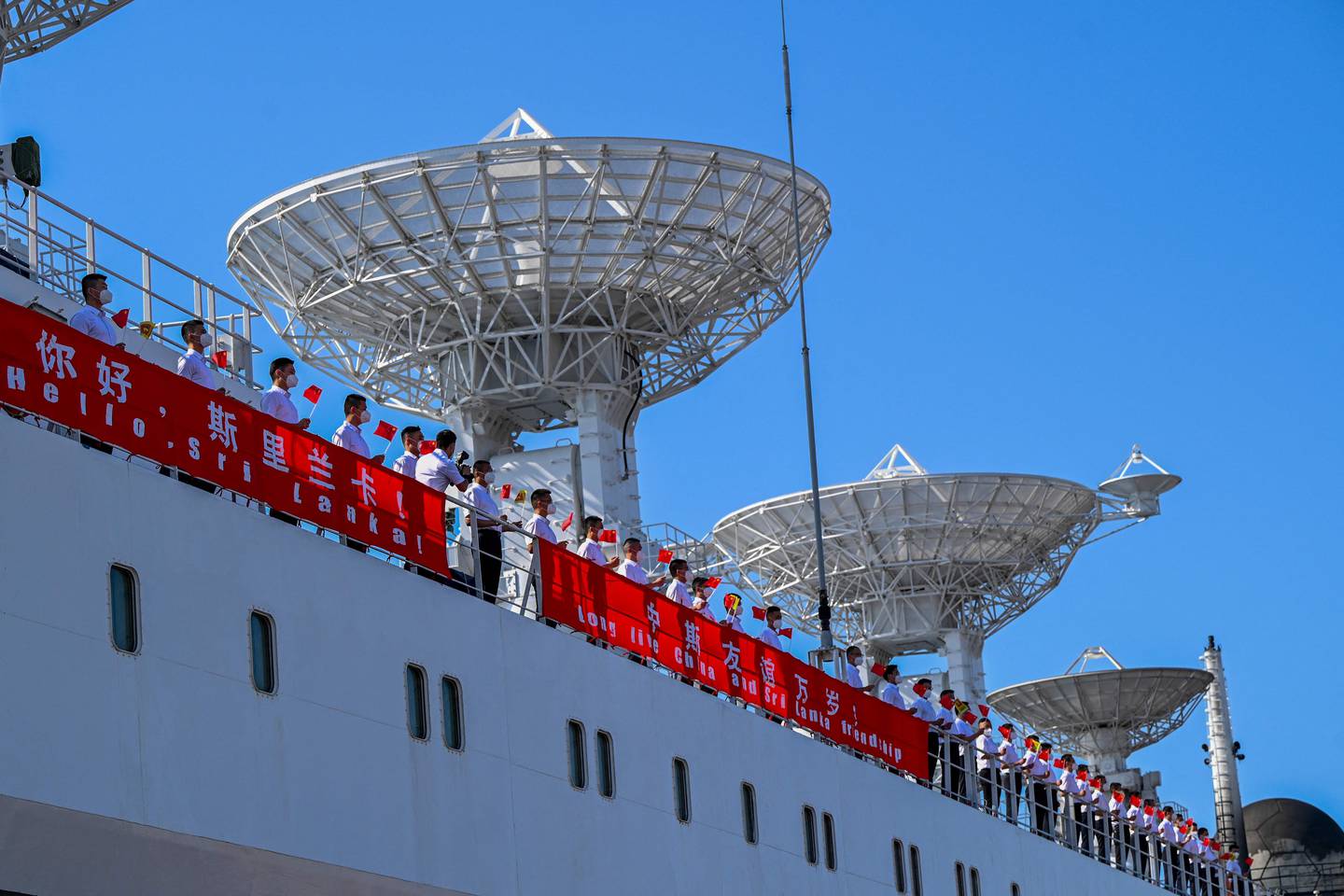 Crew members aboard China's research and survey vessel, 'the Yuan Wang 5', hold Chinese national flags upon their arrival at Hambantota port on August 16, 2022.  AFP