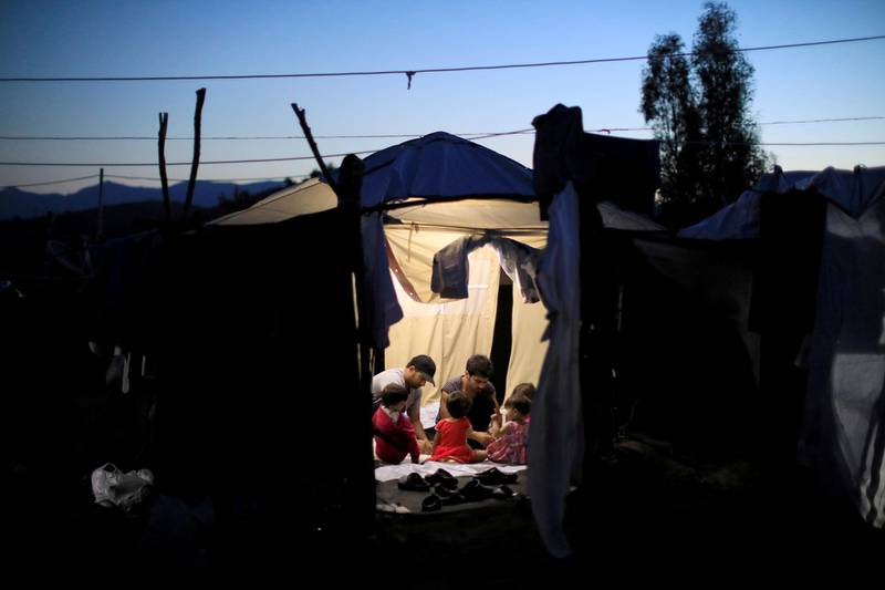FILE PHOTO: Two migrant men and four babies sit inside a tent at a makeshift camp next to the Moria camp for refugees and migrants on the island of Lesbos, Greece, September 18, 2018. Picture taken September 18, 2018. REUTERS/Giorgos Moutafis/File Photo
