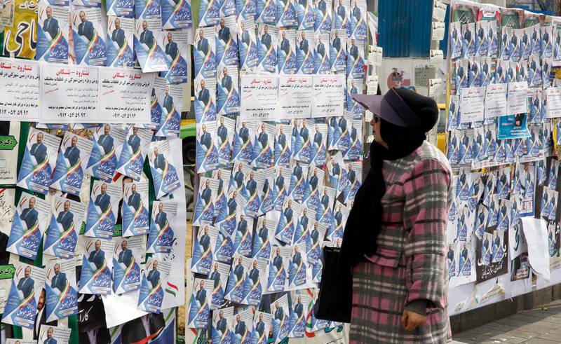 An Iranian woman looks at the electoral posters. AFP