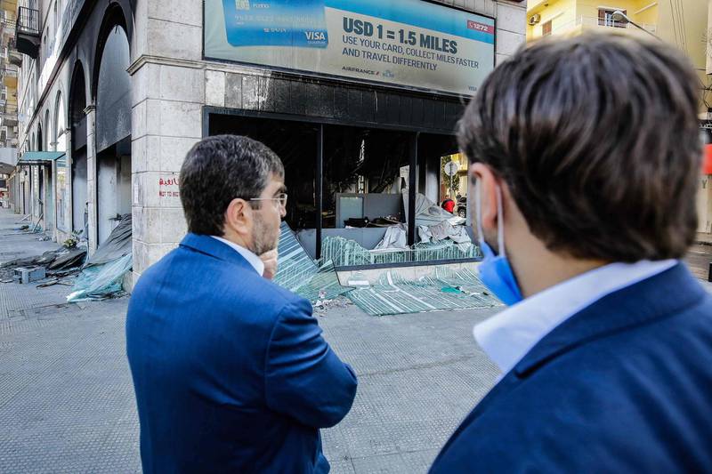 People inspect a bank set ablaze overnight by some protesters following a demonstration over the country's deteriorating economy despite a coronavirus lockdown, in the northern city of Tripoli on April 28, 2020. Lebanon is facing its worst economic crisis since the 1975-1990 civil war, now compounded by a nationwide lockdown to stem the spread of the coronavirus. The Lebanese pound has lost more than half of its value, and prices have soared.This is the case across the country, but Tripoli has been especially hard hit because more than half of its population had already been living at or below the poverty line. When mass protests erupted across Lebanon in October against perceived official graft and mismanagement, Tripoli fast became known as the "bride" of the street movement. / AFP / Ibrahim CHALHOUB

