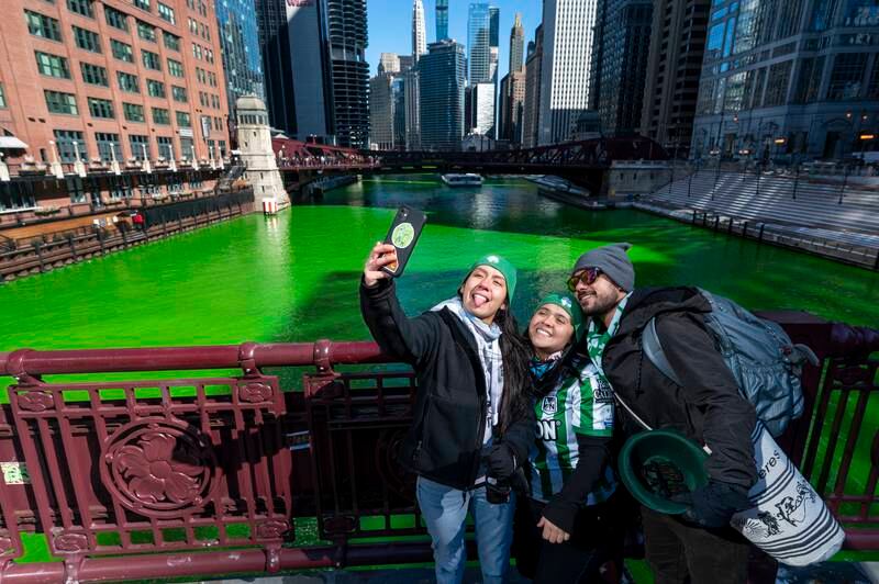 People take selfies, with the dyed-green Chicago River in the background, at the LaSalle Street Bridge, before St Patrick's Day on Thursday. AP