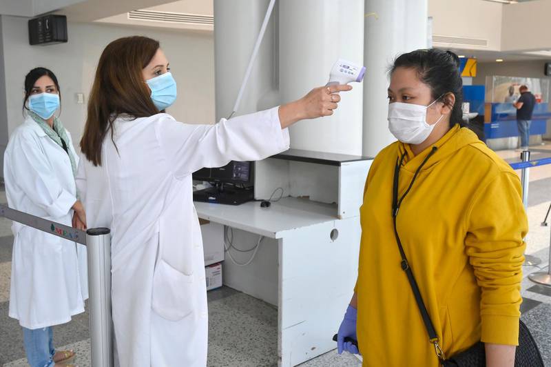 Health workers checks the temperature of a passenger at the departure terminal of the Rafik Hariri International Airport during its re-opening in Beirut. EPA