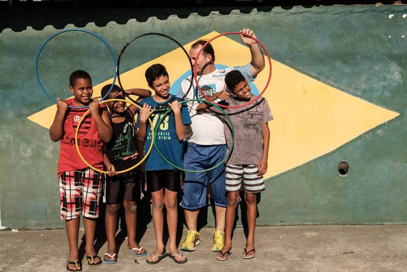 Brazilian football fan Jarbas Meneghini and neighbourhood children pose with the Olympic rings in front of his house in Rio de Janeiro. Yasuyoshi Chiba  / AFP Photo