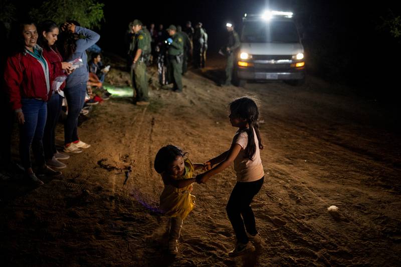 A migrant girl, 2, plays with her compatriot, 5, as border patrol agents process asylum-seekers. Reuters