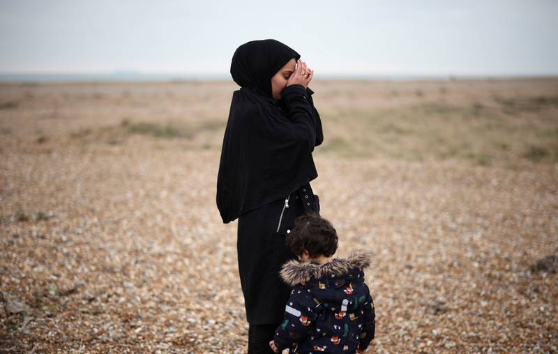 A woman with a child is brought ashore safely. Reuters