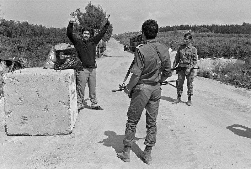 Israeli Defense Force (IDF) soldiers control 19 March 1985 a Shiite civilian at Kasmyah bridge after IDF evacuated in February about 500 sq km around Sidon (Saida), to the Litani river area, near Nabatiyeh. IDF invaded Lebanon 06 June 1982 when a force of 20,000 men crossed the border and drove northwards into Lebanon. (Photo by ESAIAS BAITEL / AFP)