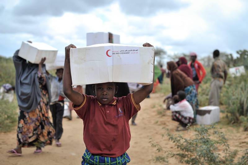 epa03813477 A handout picture provided the African Union / United Nations Information Support Team on 05 August 2013 shows a young boy carrying away a box of food from a food distribution center in Afgoye, Somalia, 04 August 2013. The UAE Red Crescent gave out food aid as part of a program they are conducting during the month of Ramadan. Over 5,000 internally displaced people were given food during the NGO's trip to Afgoye, which was aided in part by African Union Mission in Somalia (AMISOM) forces.  EPA/TOBIN JONES / AU UN IST / HANDOUT MANDATORY CREDIT AU UN IST PHOTO / TOBIN JONES HANDOUT EDITORIAL USE ONLY/NO SALES *** Local Caption ***  03813477.jpg