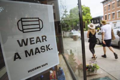 People walk past a sign reading "Wear a Mask" displayed in a shop window in Hudson, New York this week. Bloomberg