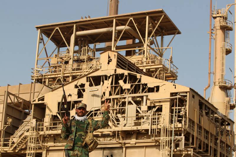 An Iraqi Shiite fighter flashes the victory sign in front of the fertiliser plant in the town of Baiji, north of Tikrit, after Iraqi forces retook the industrial area and several other neighbourhoods from ISIS, in October 2015. AFP