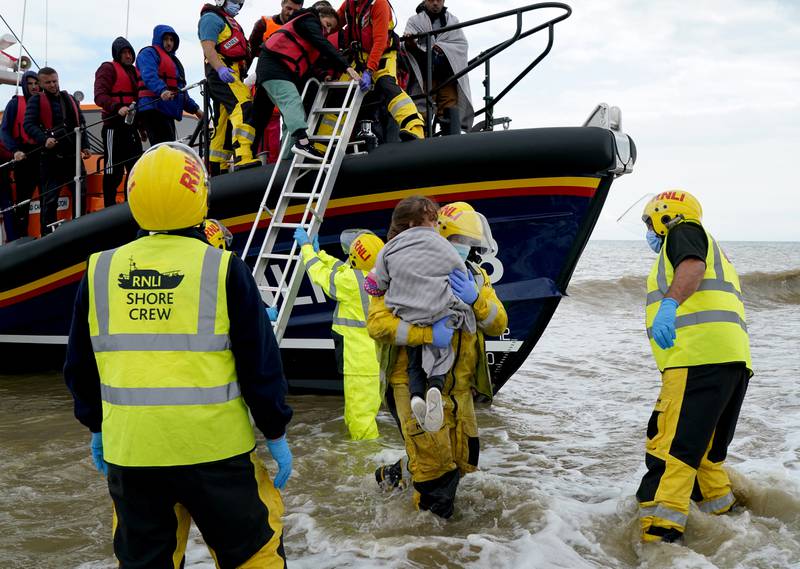 A young girl is carried to shore as migrants arrive in Dungeness, Kent, after being rescued from the English Channel by the RNLI on Thursday. PA