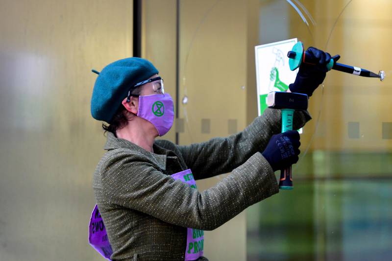 An activist hammers the windows of the Barclays offices. Reuters