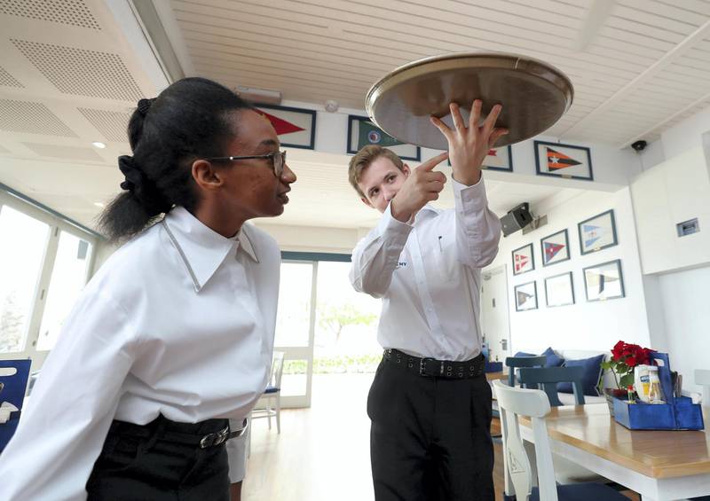 Dubai, United Arab Emirates - Reporter: Ramola Talwar: Luca Trudgeon shows fellow student Lamees Saad Omer the best way to hold a heavy tray with one hand. Students with mild to moderate learning difficulties work as servers/waiters at the Dubai Offshore Sailing Club. Monday, December 16th, 2019. Dubai Offshore sailing club, Dubai. Chris Whiteoak / The National
