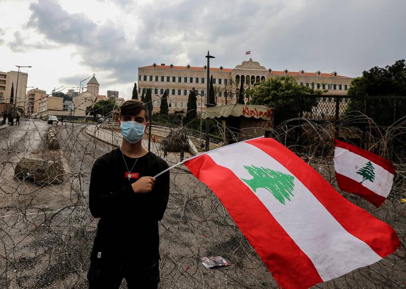 A protester waves a lebanese flag alongside a barbed wave set up to protect the government palace in downtown Beirut, Lebanon.  EPA