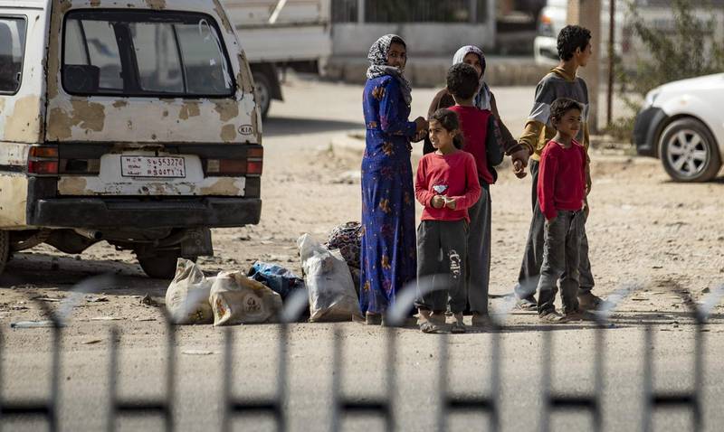 Displaced Syrians stand on the side of a road as Arab and Kurdish civilians flee amid Turkey's military assault on Kurdish-controlled areas in northeastern Syria in the Syrian border town of Tal Abyad. AFP