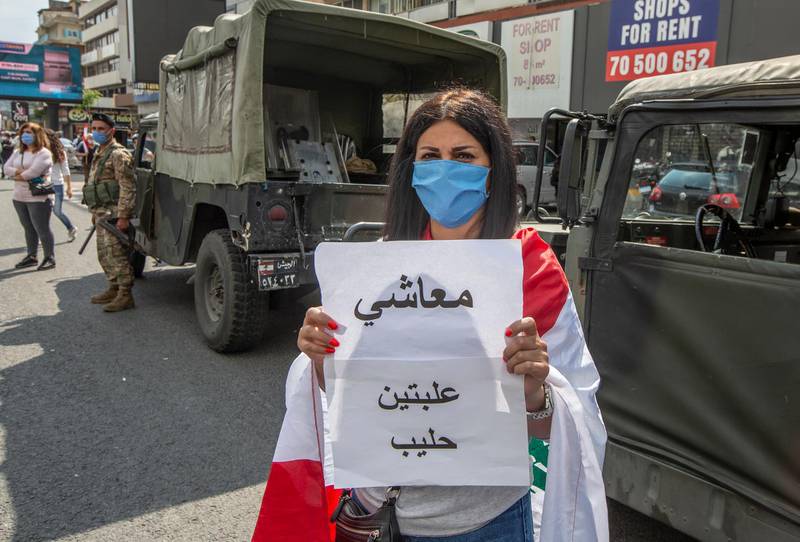 A supporter of Lebanese Christians parties carry placards with Arabic word read " My salary is not enough to buy two cans of milk " during a protest against the collapsing Lebanese pound currency and the price hikes of goods, in Al-Zouk area, northern Beirut, Lebanon.  EPA