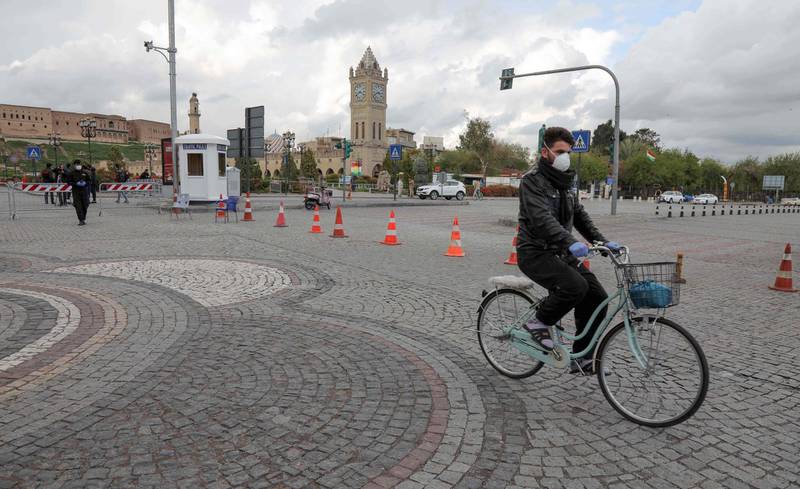 A man wearing a protective mask amid the coronavirus pandemic rides a bicycle in front of the Arbil citadel, in the eponymous capital of the northern Iraqi Kurdish autonomous region.  AFP