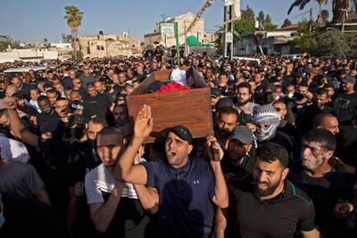 Arab Israelis gesture and wave Palestinian flags during the funeral of Mousa Hassouna in the central Israeli city of Lod near Tel Aviv.  Hassouna was killed during clashes with Israeli security following an anti-Israel demonstration over tensions in Jerusalem. AFP
