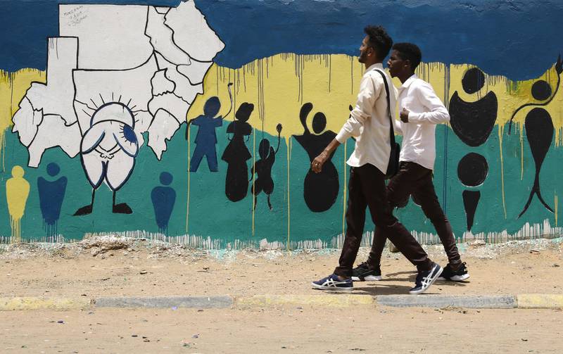 Sudanese youth walk past freshly painted graffiti. EPA