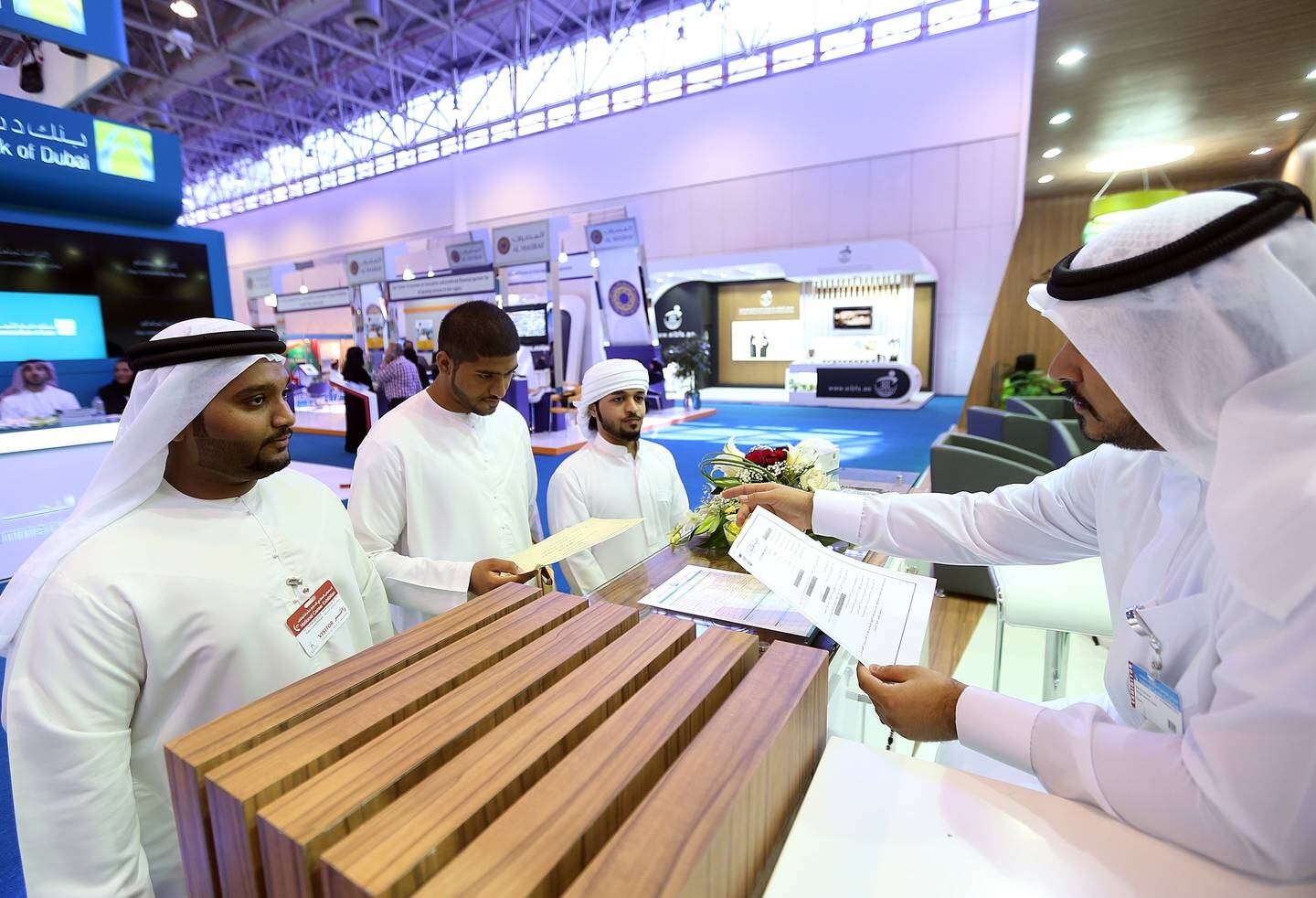 Sharjah, United Arab Emirates- February, 11, 2015:  Young emiratis ( L to  R ) Khalid Moosa Al Maazmi, Ahmed Moosa Al Maazmi and Saeed Al Shamshi from university of Sharjah  submit their  job applications to Adel Al Shirawi, recuritment officer at the Dubai Islamic Bank stand  during the National Career Exhibition at the Expo centre in Sharjah . ( Satish Kumar / The National )  For News / Story by Thaer Zuriekat Zriqat *** Local Caption ***  SK-NationalCareer-11022015-03.jpg