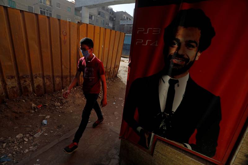 A man wearing a protective face mask walks next to a poster depicting football player Mohamed Salah of Liverpool, amid concerns over the coronavirus disease in Cairo, Egypt. Reuters