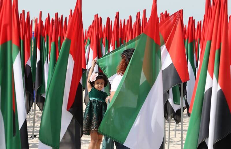 Anju Jacob takes a photo of her daughter Evelyn Dcruz, 5, at the flag garden near Kite Beach on the UAE’s 50th National Day in Dubai. Pawan Singh / The National