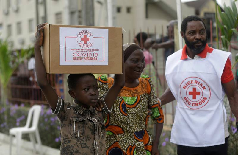 A child with his mother from Makoko Slum, carries their food parcel distributed by the Nigerian Red Cross, provided for those under coronavirus related movement restrictions, in Lagos, Nigeria. AP Photo