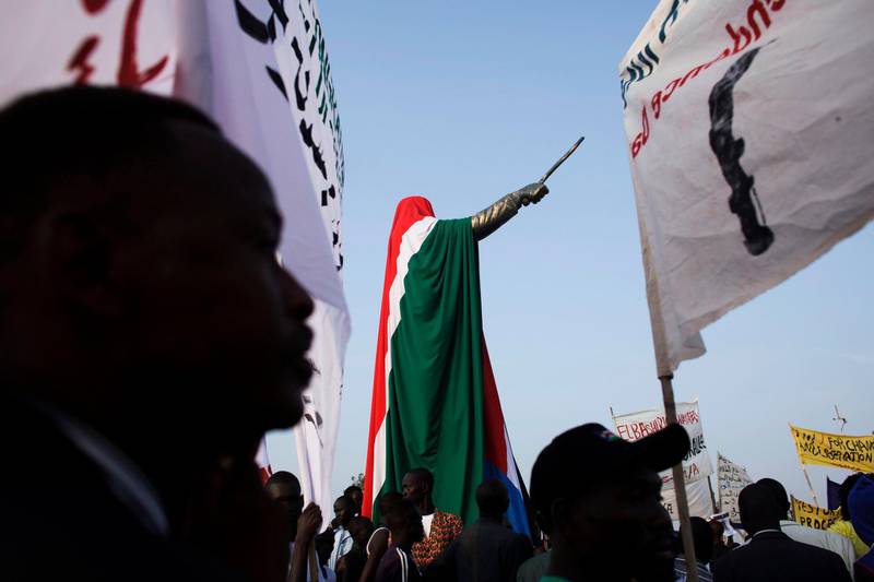 People gather around a statue of former Southern Sudanese leader John Garang, draped in the national flag of South Sudan, during independence celebrations in Juba, South Sudan, Saturday, July 9, 2011. South Sudan raised the flag of its new nation for the first time on Saturday, as thousands of South Sudanese citizens swarmed the capital of Juba to celebrate the country's birth. (AP Photo/David Azia)