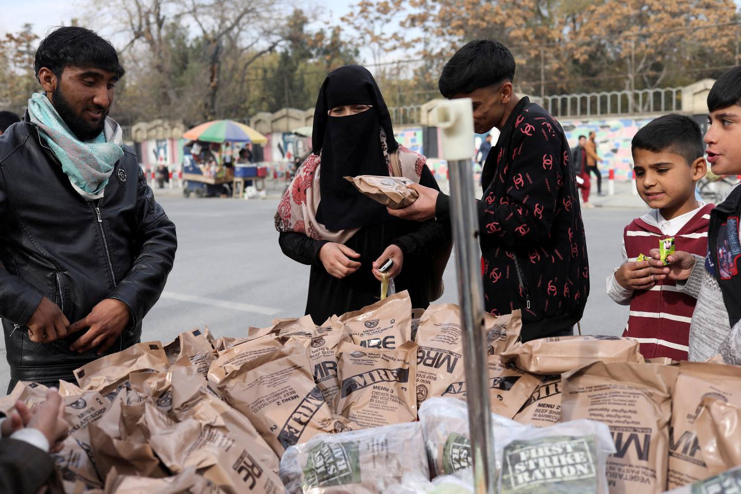 An Afghan woman buys food left behind by the US military from a peddler in Kabul, November 17. Reuters