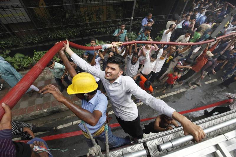 Locals help firefighters outside the office building in Dhaka. AP Photo