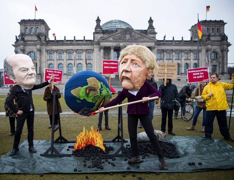 Activists portraying themselves as Olaf Scholz, left, and Angela Merkel, right, accuse Germany's government of burning the Earth. AFP