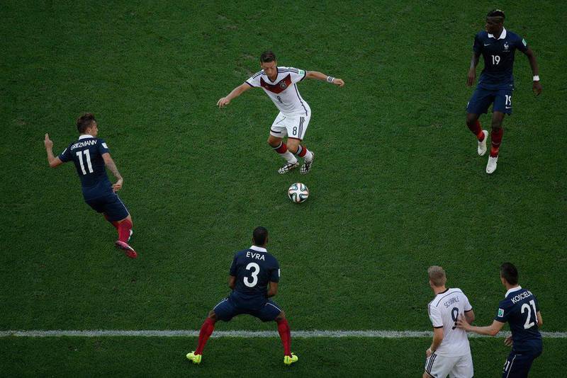 Mesut Ozil, centre, of Germany dribbles around French players while Andre Schurrle, No 9, looks on during Germany's quarter-finals victory over France at the 2014 World Cup on Friday. Matt Dunham / AP / July 4, 2014