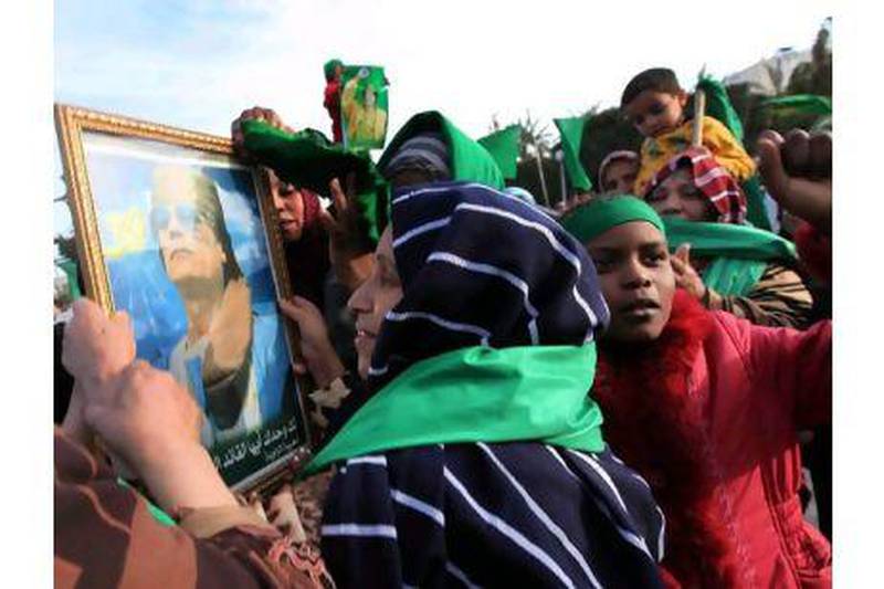 Libyans supporting leader Muammar Qaddafi hold his portrait in the city of Zawiya, west of Tripoli. One reader urges Arab intervention in the conflict while another explains regional support for Qaddafi. Stringer/EPA