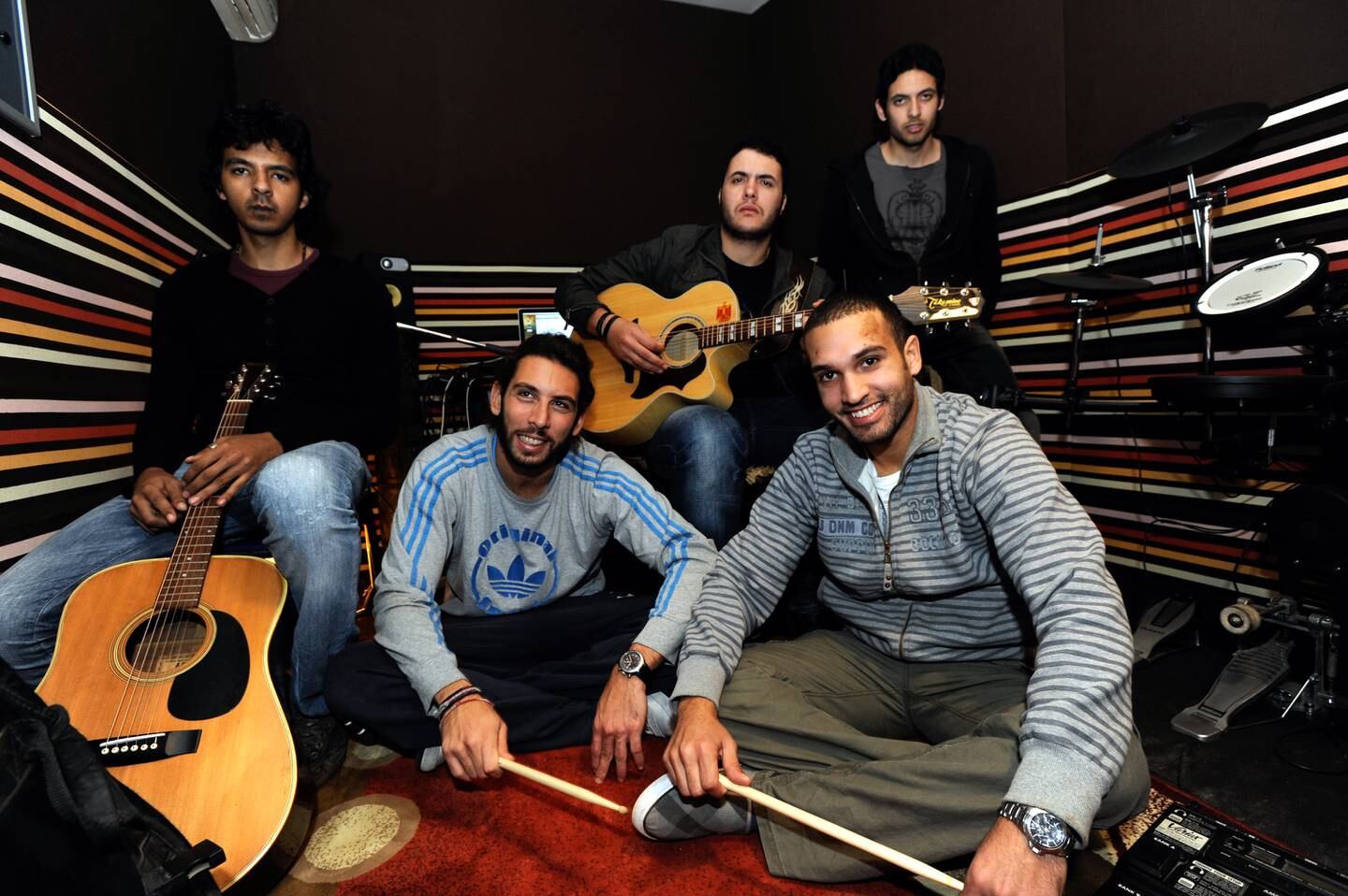 15 décembre 2011 - Le Caire, Égypte : Sherif Hawary, Amir Eid, Sherif Mustafa (LR assis sur des chaises) ;  Tamer Hashem et Adam El Alfy (LR assis par terre) du groupe populaire Cairokee photographiés dans leur petit studio chez Eid à Maadi.  (Dana Smillie pour The National)